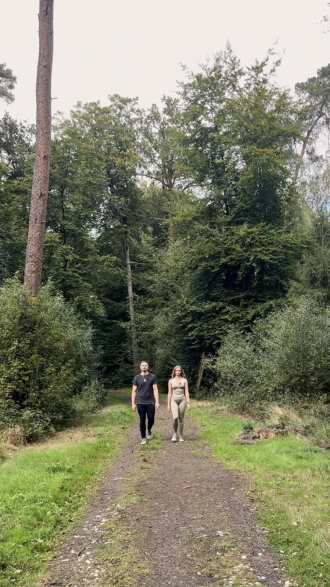 Outdoor-Training im Alltag: zwei Personen gehen auf einem Waldweg in der Natur.