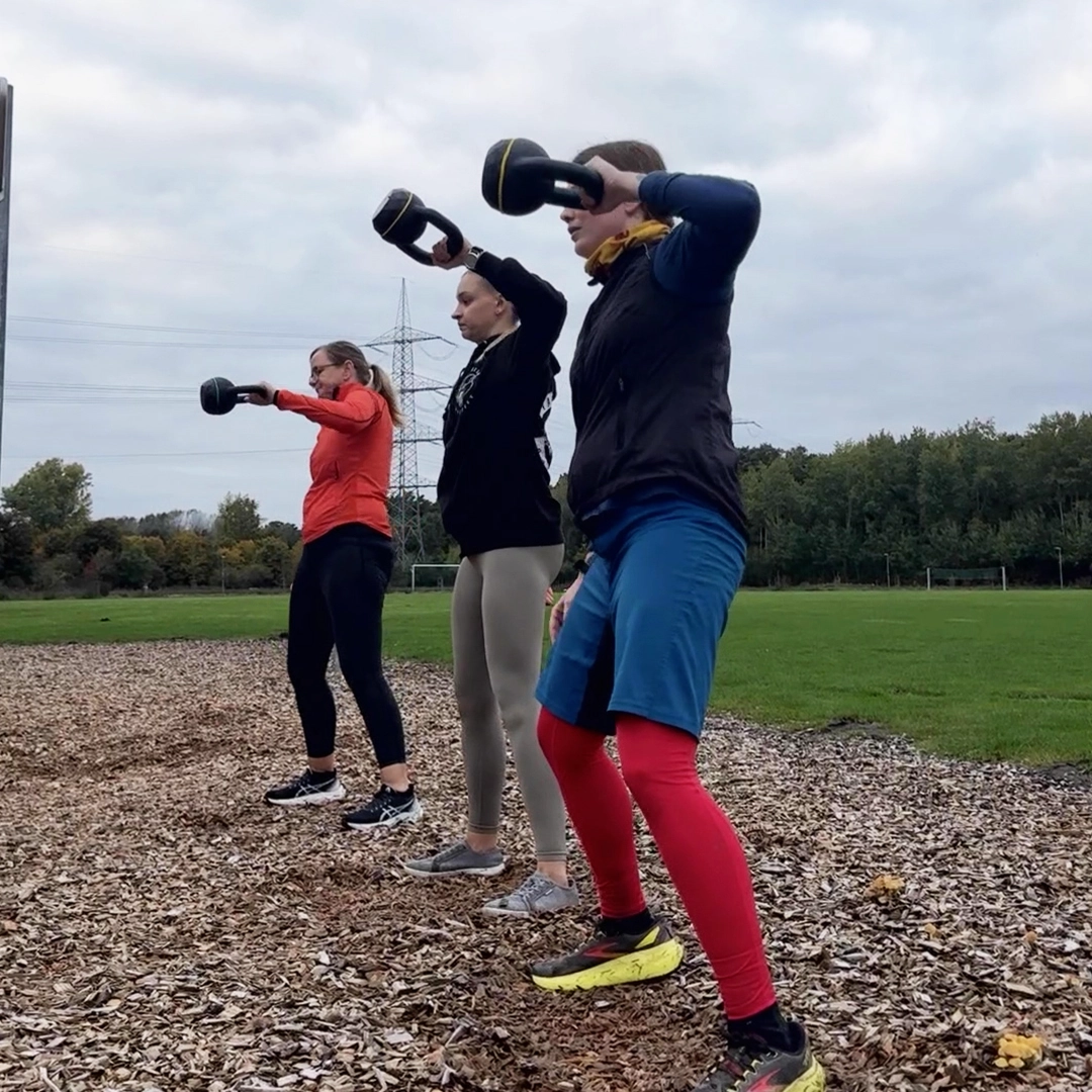3 Frauen stehen in einer Reihe und machen einen Kettlebell High Pull.