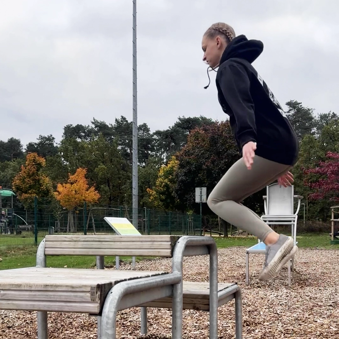 Eine Frau springt auf eine Erhöhung.