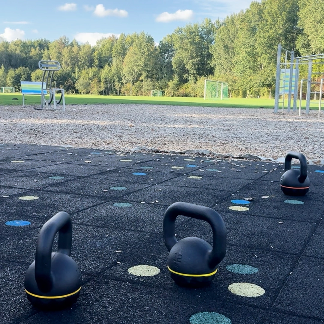 3 Kettlebells stehen auf dem Boden eines Calisthenicsparks.